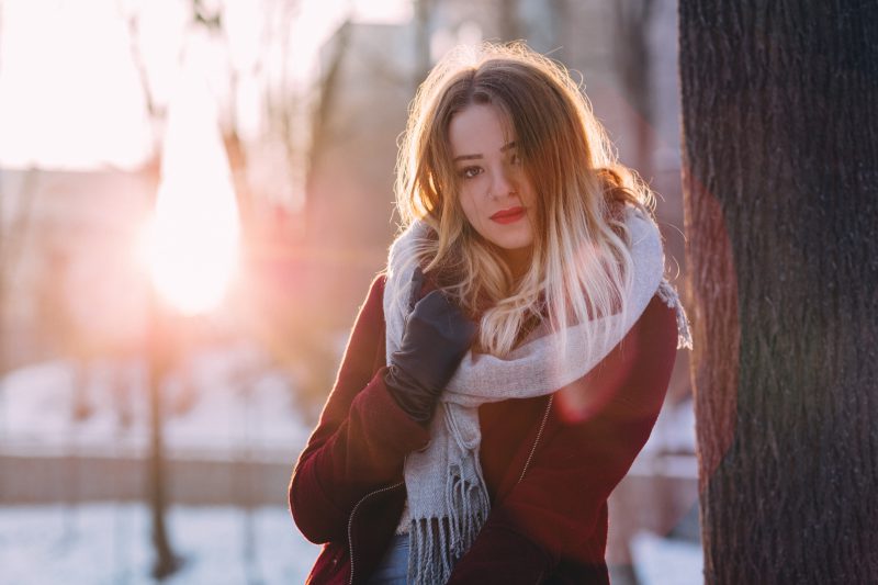 kobieta w zimowej kurtce i szaliku pozuje do zdjęcia